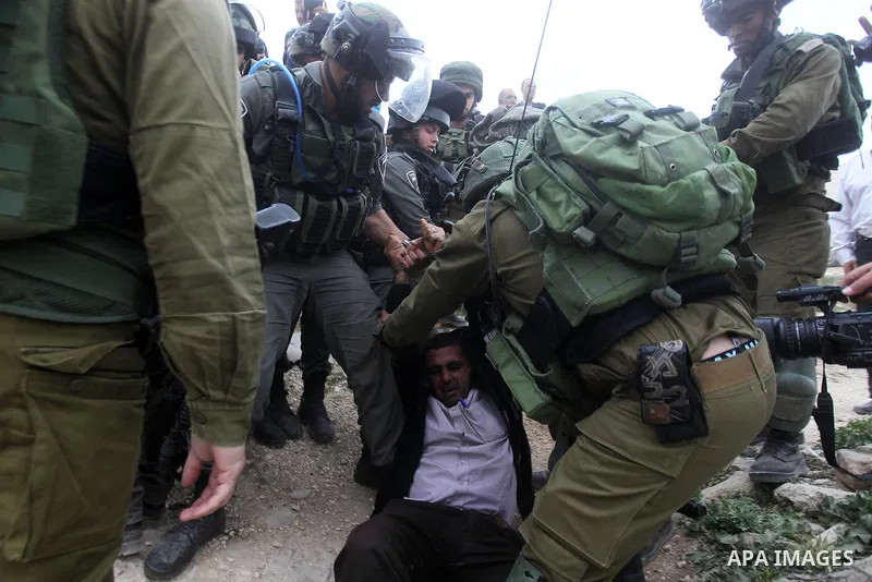 Israeli troops detain a Palestinian demonstrator during a protest marking Land Day in the West Bank city of Hebron March 30, 2017. Photo by Wisam Hashlamoun