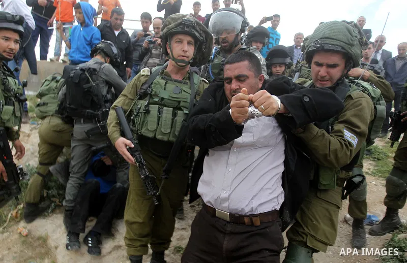 Israeli troops detain a Palestinian demonstrator during a protest marking Land Day in the West Bank city of Hebron March 30, 2017. Photo by Wisam Hashlamoun
