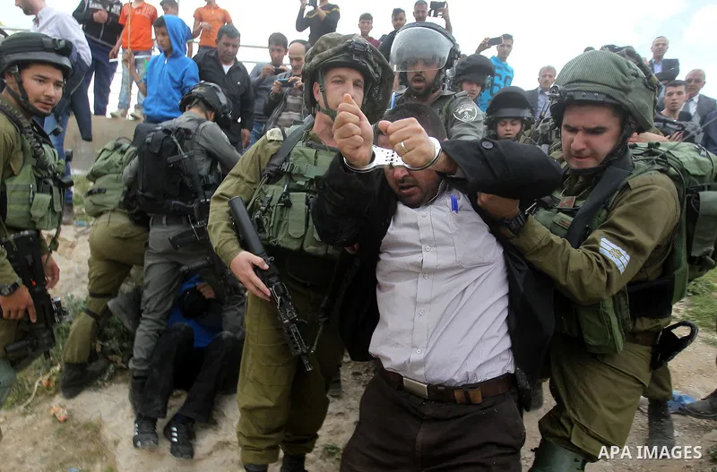 Israeli troops detain a Palestinian demonstrator during a protest marking Land Day in the West Bank city of Hebron March 30, 2017. Photo by Wisam Hashlamoun