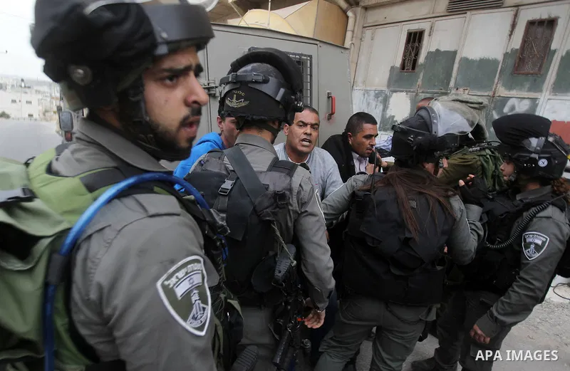 Israeli troops detain a Palestinian demonstrator during a protest marking Land Day in the West Bank city of Hebron March 30, 2017. Photo by Wisam Hashlamoun