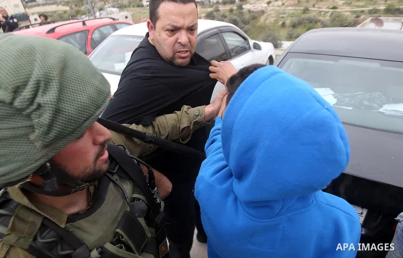 Israeli troops detain a Palestinian demonstrator during a protest marking Land Day in the West Bank city of Hebron March 30, 2017. Photo by Wisam Hashlamoun