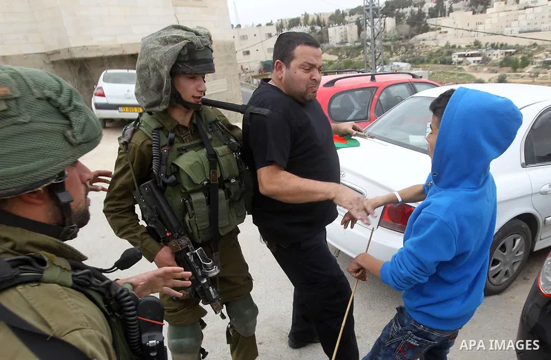 Israeli troops detain a Palestinian demonstrator during a protest marking Land Day in the West Bank city of Hebron March 30, 2017. Photo by Wisam Hashlamoun