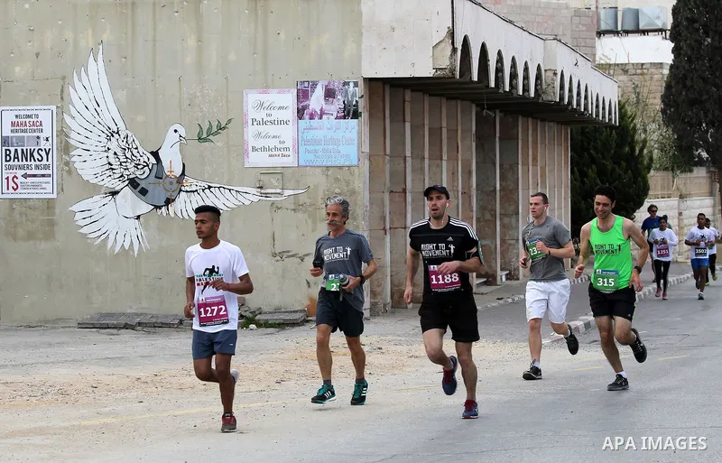 Participants run in the biblical West Bank town of Bethlehem during the 5th Palestine Marathon on March 31, 2017. Photo by Wisam Hashlamoun