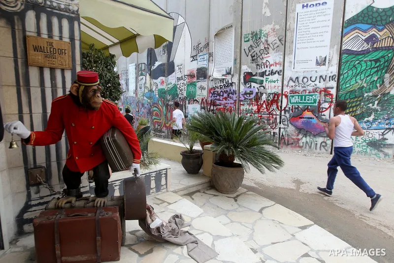 Participants run past the the Walled-Off Hotel, Banksy's newly opened hotel, next to Israel's controversial separation wall, during the fifth Palestine Marathon in the biblical West Bank town of Bethlehem, on March 31, 2...