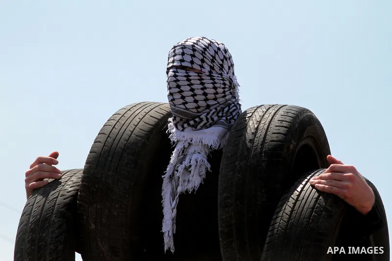 A Palestinian protester carries tires during clashes with Israeli security forces following a weekly demonstration against the expropriation of Palestinian land by Israel in the village of Kfar Qaddum, near Nablus, in th...