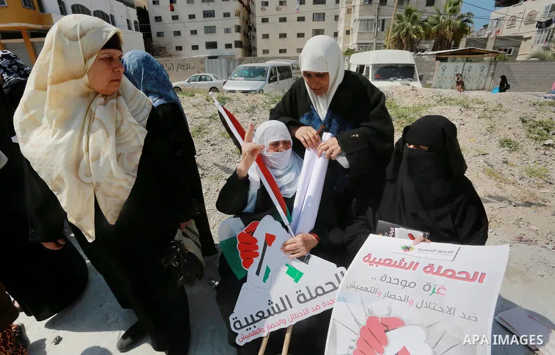 Palestinian activists take part in a rally titled "save Gaza" against the Israeli occupation and Gaza blockade in front of a tower which was destroy during the 50-day war between Israel and Hamas militants in the summer...
