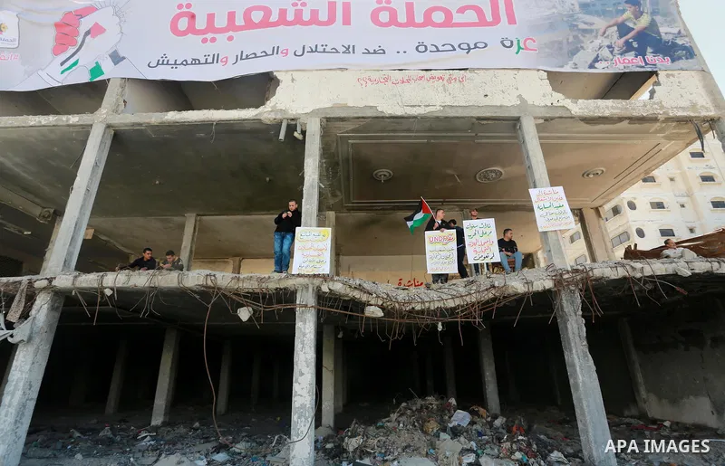 Palestinian activists take part in a rally titled "save Gaza" against the Israeli occupation and Gaza blockade in front of a tower which was destroy during the 50-day war between Israel and Hamas militants in the summer...