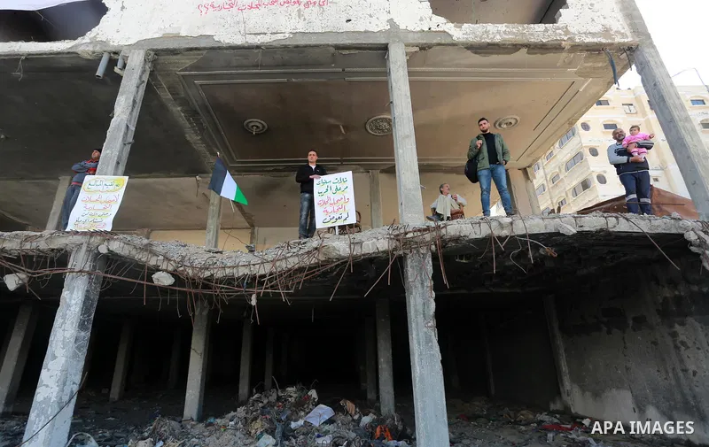 Palestinian activists take part in a rally titled "save Gaza" against the Israeli occupation and Gaza blockade in front of a tower which was destroy during the 50-day war between Israel and Hamas militants in the summer...