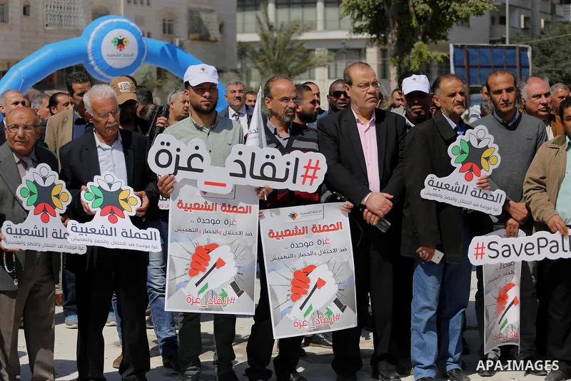 Palestinian activists take part in a rally titled "save Gaza" against the Israeli occupation and Gaza blockade in front of a tower which was destroy during the 50-day war between Israel and Hamas militants in the summer...