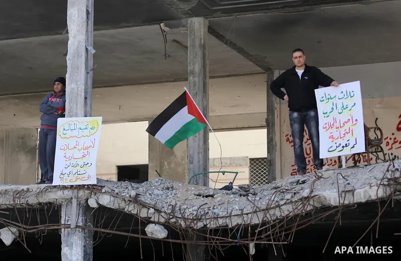 Palestinian activists take part in a rally titled "save Gaza" against the Israeli occupation and Gaza blockade in front of a tower which was destroy during the 50-day war between Israel and Hamas militants in the summer...