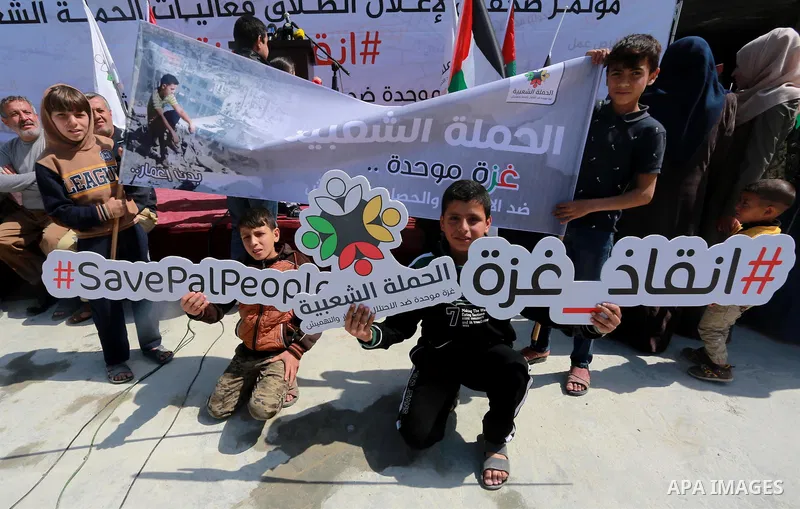 Palestinian activists take part in a rally titled "save Gaza" against the Israeli occupation and Gaza blockade in front of a tower which was destroy during the 50-day war between Israel and Hamas militants in the summer...