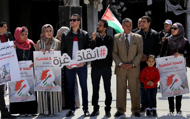 Palestinian activists take part in a rally titled "save Gaza" against the Israeli occupation and Gaza blockade in front of a tower which was destroy during the 50-day war between Israel and Hamas militants in the summer...