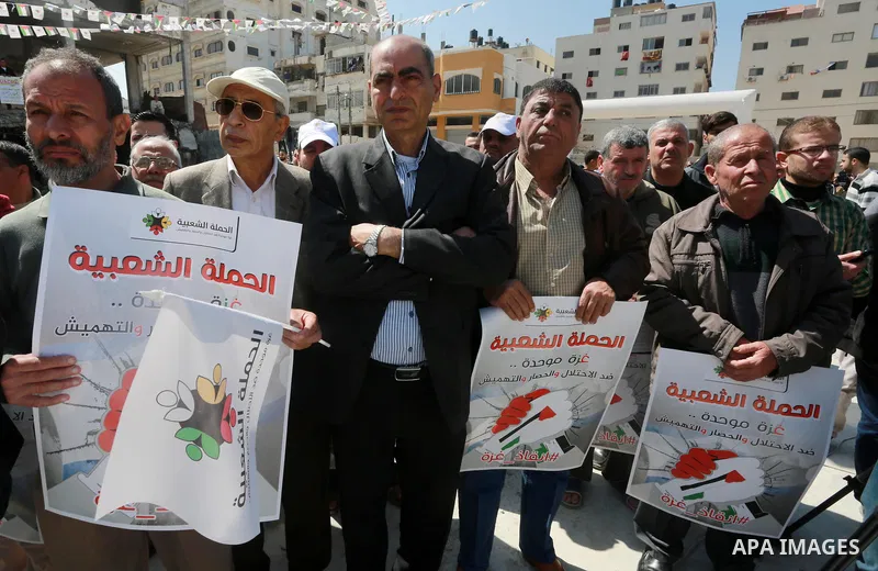 Palestinian activists take part in a rally titled "save Gaza" against the Israeli occupation and Gaza blockade in front of a tower which was destroy during the 50-day war between Israel and Hamas militants in the summer...