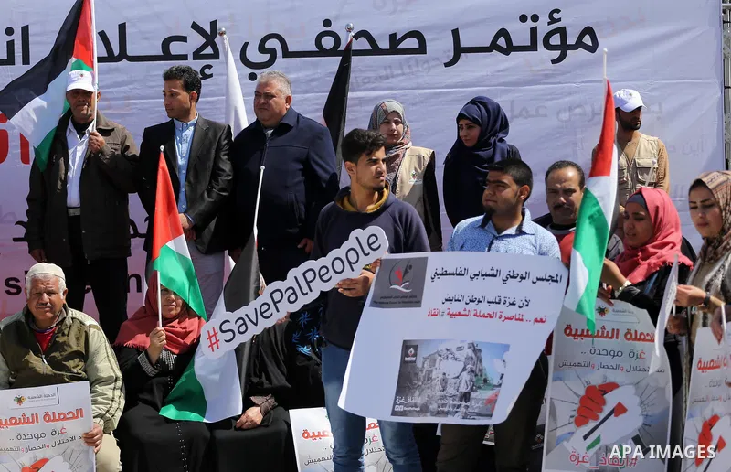 Palestinian activists take part in a rally titled "save Gaza" against the Israeli occupation and Gaza blockade in front of a tower which was destroy during the 50-day war between Israel and Hamas militants in the summer...