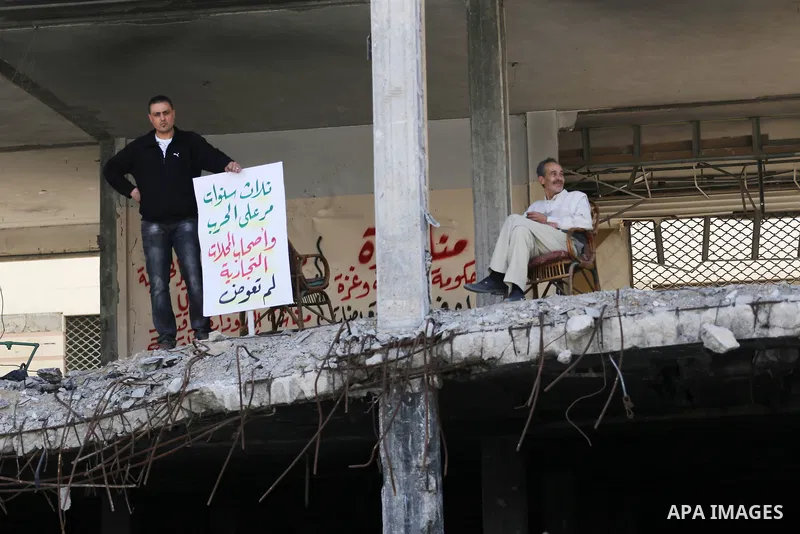 Palestinian activists take part in a rally titled "save Gaza" against the Israeli occupation and Gaza blockade in front of a tower which was destroy during the 50-day war between Israel and Hamas militants in the summer...