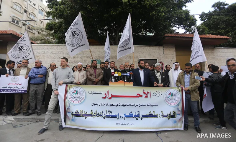 Palestinians hold placards during a protest to show solidarity with Palestinian prisoners held in Israeli Jails, in front of Red cross office in Gaza city, on April 2, 2017. Photo by Mohammed Asad