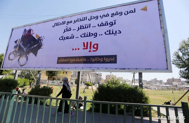 Palestinians walk past a banner announcing the launch of a campaign against collaborating with Israel, in Gaza city, on April 04, 2017, as the ruling Ministry of Interior in the Gaza Strip launches a week-long campaign t...