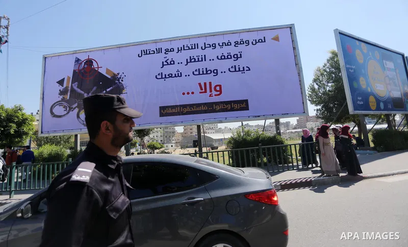 Palestinians walk past a banner announcing the launch of a campaign against collaborating with Israel, in Gaza city, on April 04, 2017, as the ruling Ministry of Interior in the Gaza Strip launches a week-long campaign t...