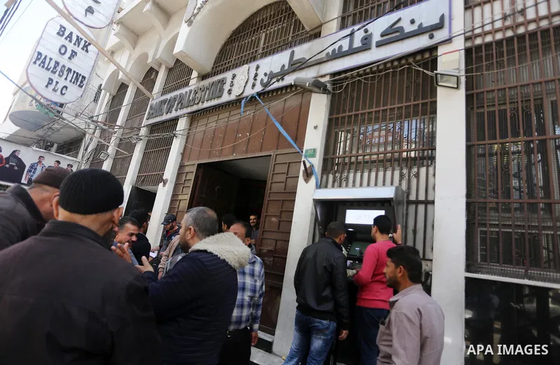 Palestinian employees paid by the Palestinian Authority wait to receive their salaries from an ATM, outside a Bank in Gaza City April 5, 2017. The salaries of Palestinian employees in Gaza strip have been reduced by abou...
