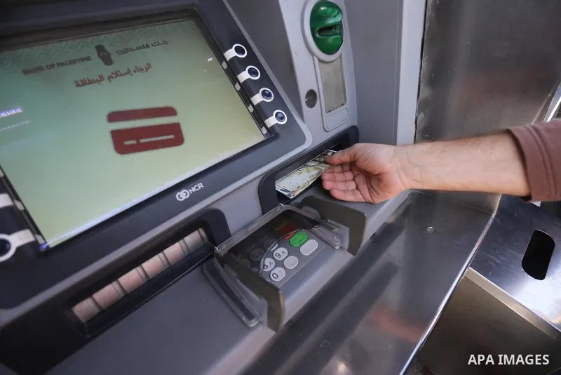 Palestinian employees paid by the Palestinian Authority wait to receive their salaries from an ATM, outside a Bank in Gaza City April 5, 2017. The salaries of Palestinian employees in Gaza strip have been reduced by abou...