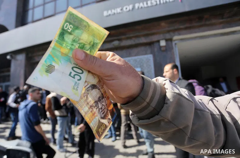 Palestinian employees paid by the Palestinian Authority wait to receive their salaries from an ATM, outside a Bank in Gaza City April 5, 2017. The salaries of Palestinian employees in Gaza strip have been reduced by abou...