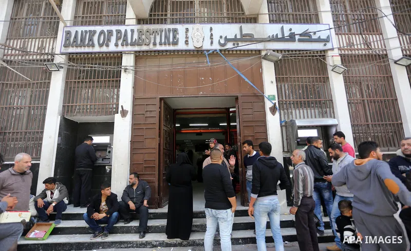 Palestinian employees paid by the Palestinian Authority wait to receive their salaries from an ATM, outside a Bank in Gaza City April 5, 2017. The salaries of Palestinian employees in Gaza strip have been reduced by abou...