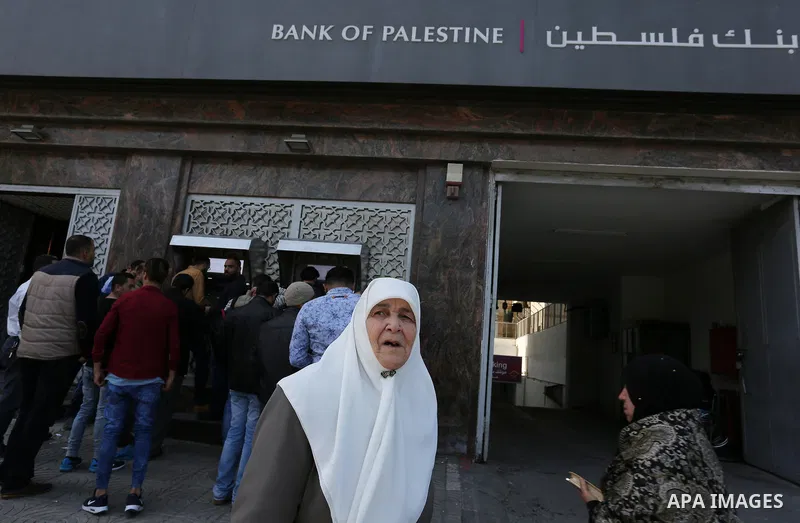 Palestinian employees paid by the Palestinian Authority wait to receive their salaries from an ATM, outside a Bank in Gaza City April 5, 2017. The salaries of Palestinian employees in Gaza strip have been reduced by abou...