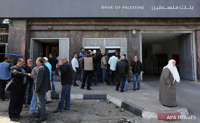Palestinian employees paid by the Palestinian Authority wait to receive their salaries from an ATM, outside a Bank in Gaza City April 5, 2017. The salaries of Palestinian employees in Gaza strip have been reduced by abou...