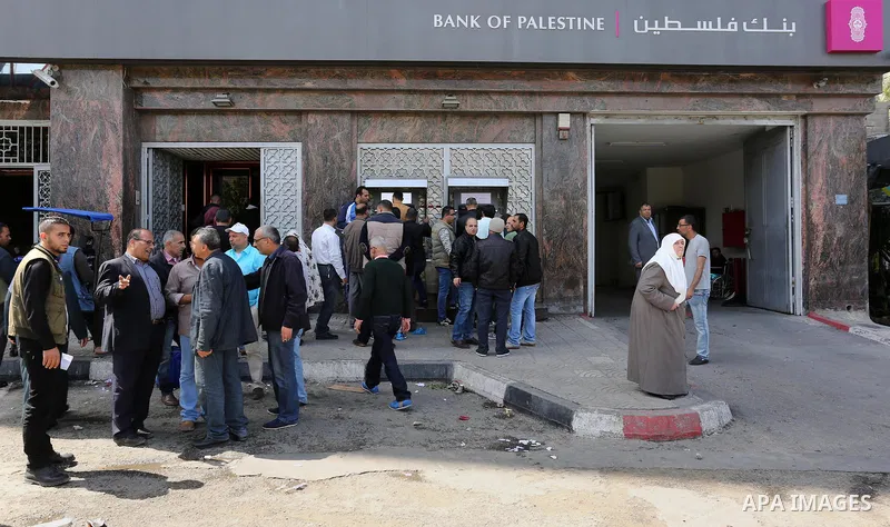 Palestinian employees paid by the Palestinian Authority wait to receive their salaries from an ATM, outside a Bank in Gaza City April 5, 2017. The salaries of Palestinian employees in Gaza strip have been reduced by abou...