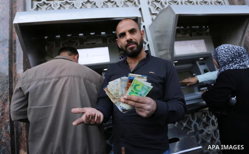 Palestinian employees paid by the Palestinian Authority wait to receive their salaries from an ATM, outside a Bank in Gaza City April 5, 2017. The salaries of Palestinian employees in Gaza strip have been reduced by abou...
