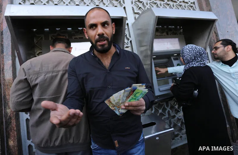 Palestinian employees paid by the Palestinian Authority wait to receive their salaries from an ATM, outside a Bank in Gaza City April 5, 2017. The salaries of Palestinian employees in Gaza strip have been reduced by abou...