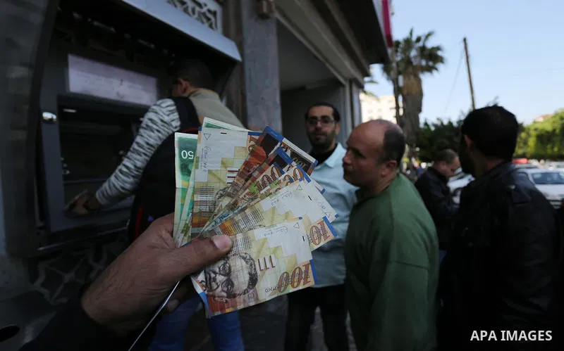 Palestinian employees paid by the Palestinian Authority wait to receive their salaries from an ATM, outside a Bank in Gaza City April 5, 2017. The salaries of Palestinian employees in Gaza strip have been reduced by abou...