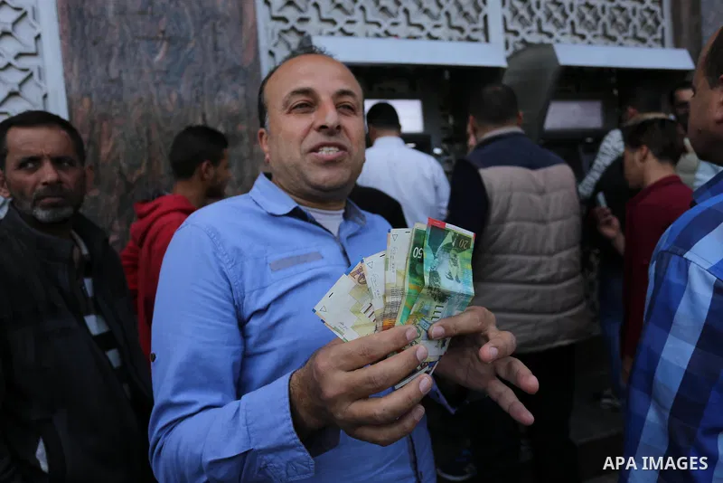 Palestinian employees paid by the Palestinian Authority wait to receive their salaries from an ATM, outside a Bank in Gaza City April 5, 2017. The salaries of Palestinian employees in Gaza strip have been reduced by abou...