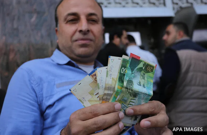 Palestinian employees paid by the Palestinian Authority wait to receive their salaries from an ATM, outside a Bank in Gaza City April 5, 2017. The salaries of Palestinian employees in Gaza strip have been reduced by abou...