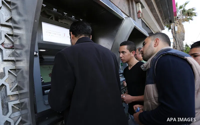 Palestinian employees paid by the Palestinian Authority wait to receive their salaries from an ATM, outside a Bank in Gaza City April 5, 2017. The salaries of Palestinian employees in Gaza strip have been reduced by abou...