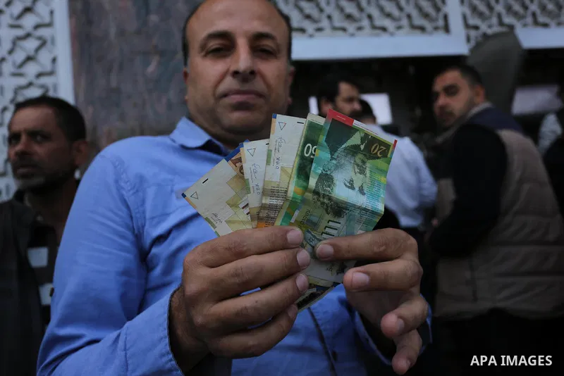 Palestinian employees paid by the Palestinian Authority wait to receive their salaries from an ATM, outside a Bank in Gaza City April 5, 2017. The salaries of Palestinian employees in Gaza strip have been reduced by abou...
