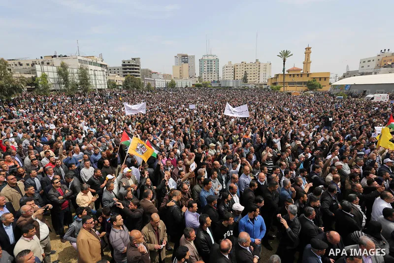 Palestinians, employed by the Palestinian Authority, chant slogans and wave placards during a demonstration against the decision to reduce their salaries in Gaza City on April 8, 2017. Photo by Ashraf Amra
