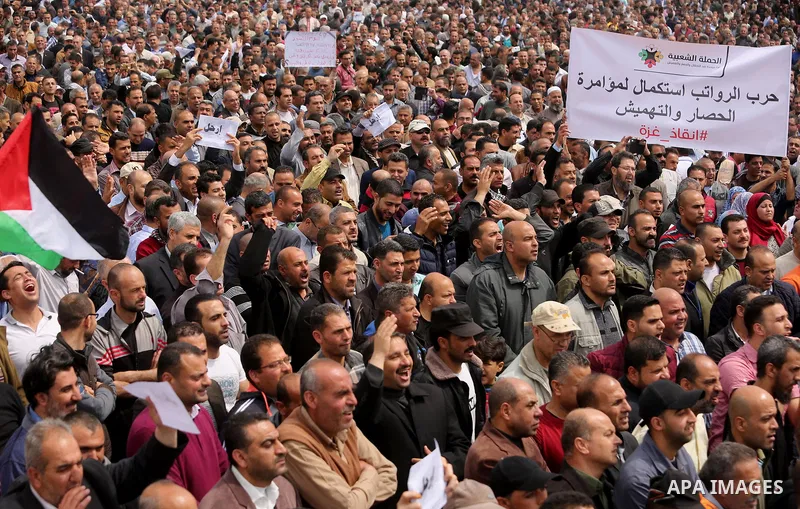 Palestinians, employed by the Palestinian Authority, chant slogans and wave placards during a demonstration against the decision to reduce their salaries in Gaza City on April 8, 2017. Photo by Ashraf Amra