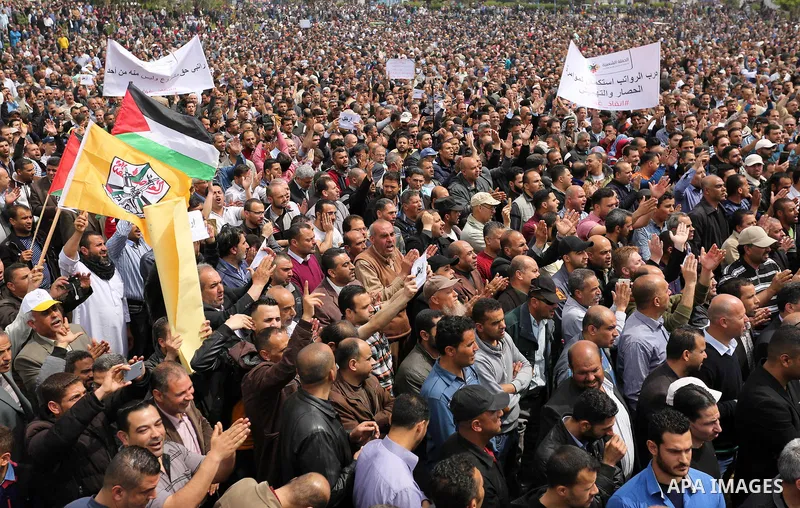 Palestinians, employed by the Palestinian Authority, chant slogans and wave placards during a demonstration against the decision to reduce their salaries in Gaza City on April 8, 2017. Photo by Ashraf Amra