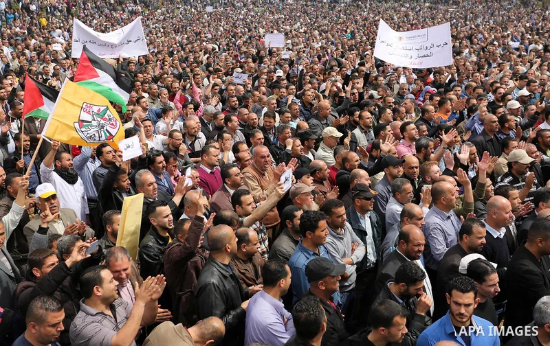 Palestinians, employed by the Palestinian Authority, chant slogans and wave placards during a demonstration against the decision to reduce their salaries in Gaza City on April 8, 2017. Photo by Ashraf Amra