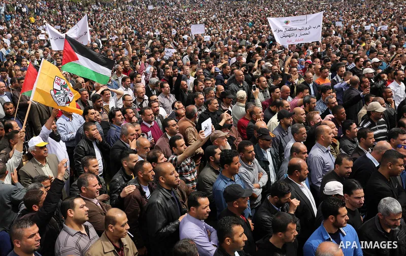 Palestinians, employed by the Palestinian Authority, chant slogans and wave placards during a demonstration against the decision to reduce their salaries in Gaza City on April 8, 2017. Photo by Ashraf Amra
