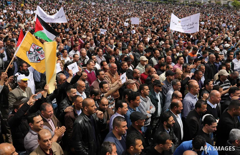 Palestinians, employed by the Palestinian Authority, chant slogans and wave placards during a demonstration against the decision to reduce their salaries in Gaza City on April 8, 2017. Photo by Ashraf Amra