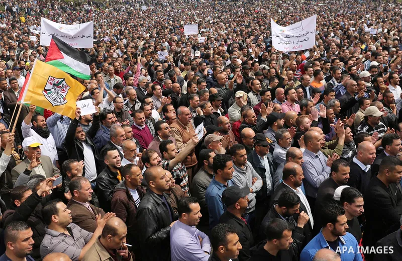 Palestinians, employed by the Palestinian Authority, chant slogans and wave placards during a demonstration against the decision to reduce their salaries in Gaza City on April 8, 2017. Photo by Ashraf Amra