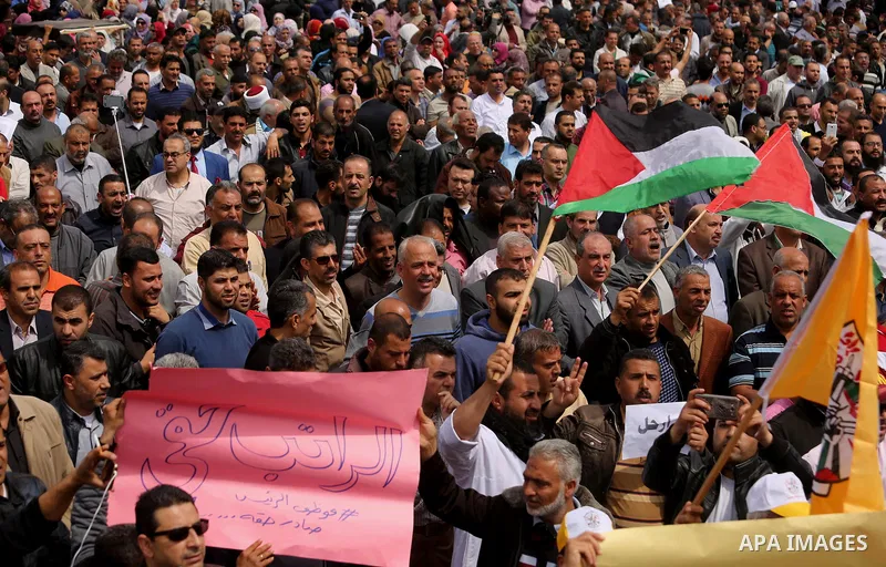 Palestinians, employed by the Palestinian Authority, chant slogans and wave placards during a demonstration against the decision to reduce their salaries in Gaza City on April 8, 2017. Photo by Ashraf Amra
