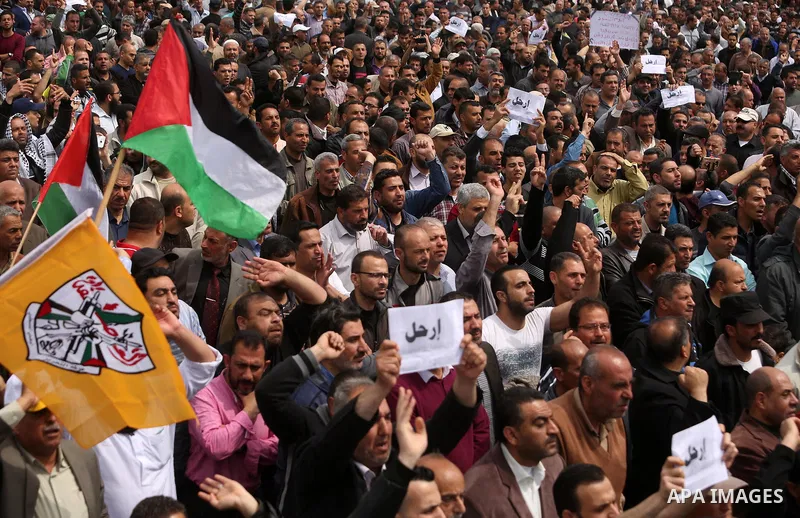 Palestinians, employed by the Palestinian Authority, chant slogans and wave placards during a demonstration against the decision to reduce their salaries in Gaza City on April 8, 2017. Photo by Ashraf Amra