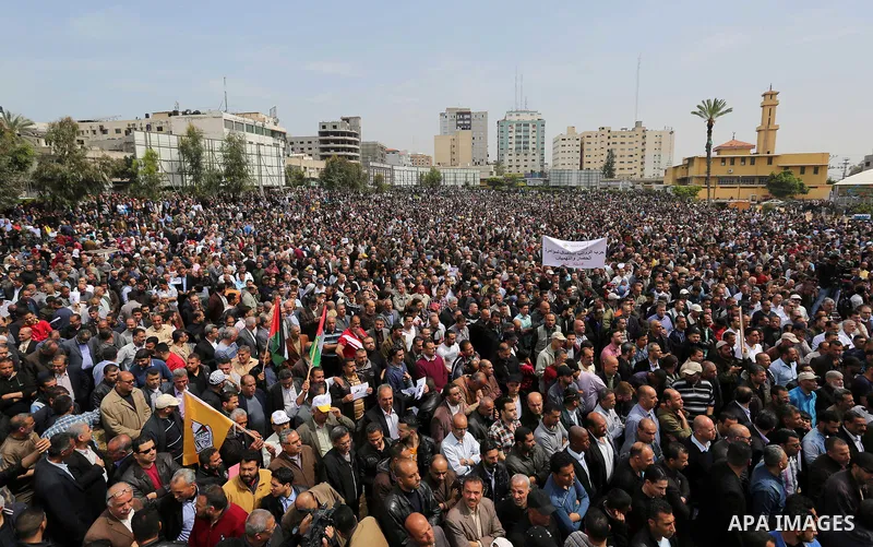 Palestinians, employed by the Palestinian Authority, chant slogans and wave placards during a demonstration against the decision to reduce their salaries in Gaza City on April 8, 2017. Photo by Ashraf Amra