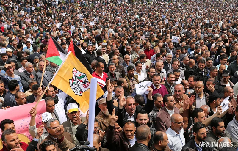 Palestinians, employed by the Palestinian Authority, chant slogans and wave placards during a demonstration against the decision to reduce their salaries in Gaza City on April 8, 2017. Photo by Ashraf Amra