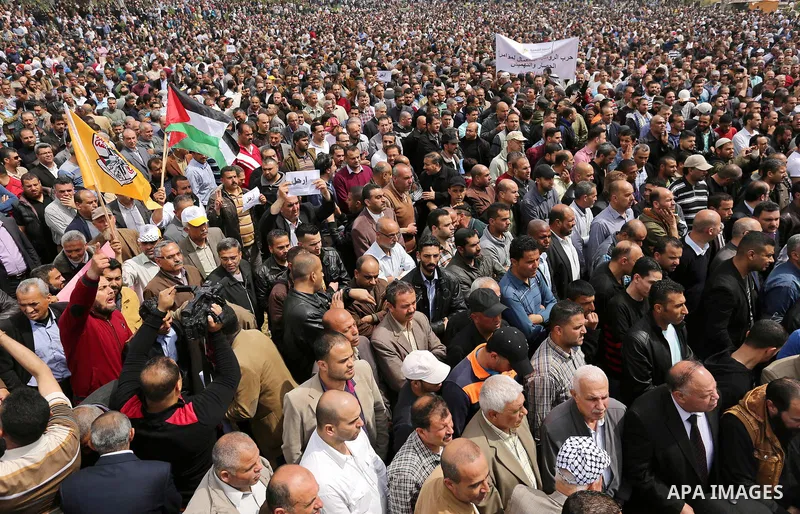 Palestinians, employed by the Palestinian Authority, chant slogans and wave placards during a demonstration against the decision to reduce their salaries in Gaza City on April 8, 2017. Photo by Ashraf Amra