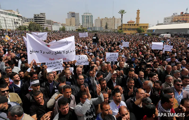 Palestinians, employed by the Palestinian Authority, chant slogans and wave placards during a demonstration against the decision to reduce their salaries in Gaza City on April 8, 2017. Photo by Ashraf Amra