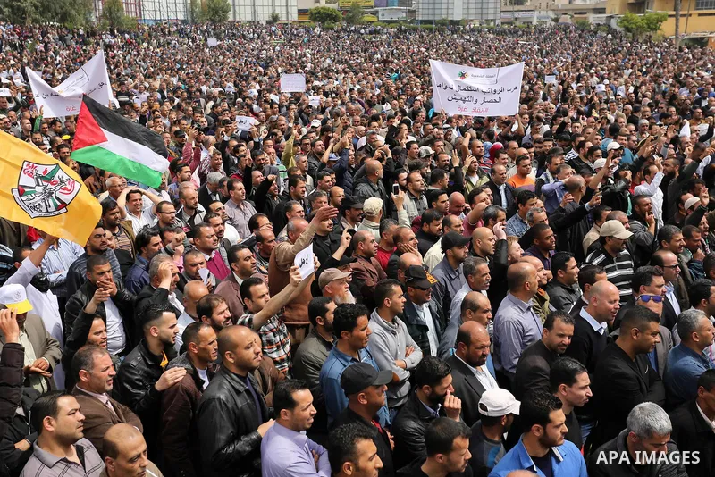 Palestinians, employed by the Palestinian Authority, chant slogans and wave placards during a demonstration against the decision to reduce their salaries in Gaza City on April 8, 2017. Photo by Ashraf Amra